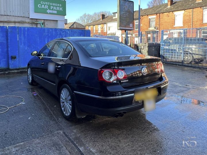 Louis's black Volkswagen Passat saloon, parked on a wet forecourt