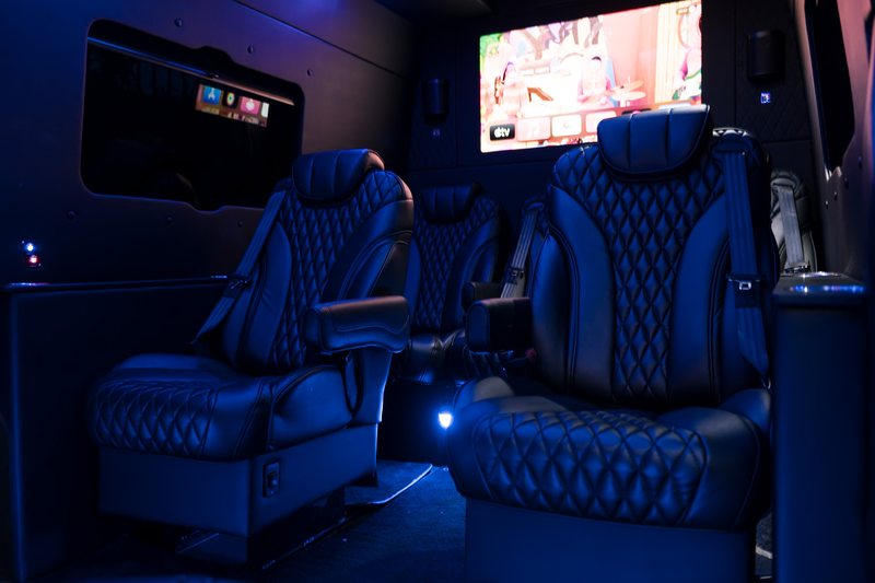 The cabin of the R5 Sprinter at night, with quilted leather seats, blue ambient lighting and a screen